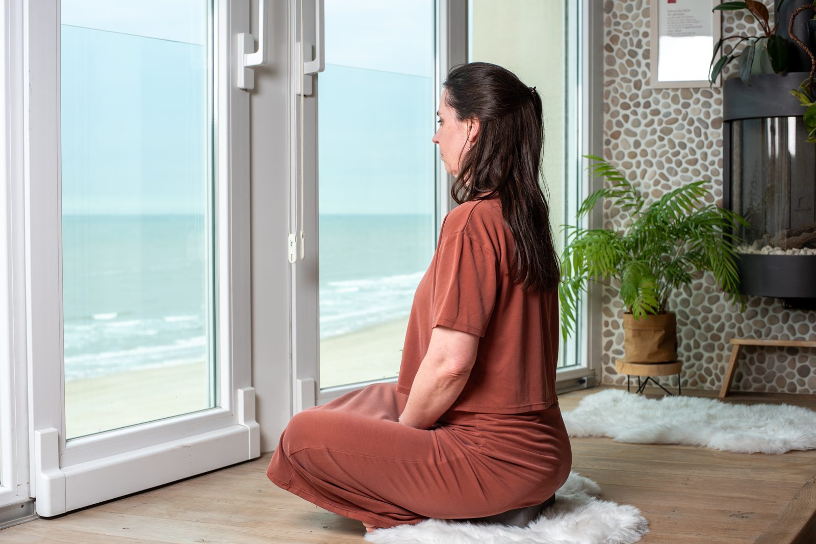 Liese sitting on a rug, looking out at the sea